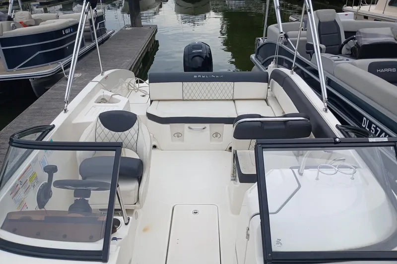 Slide: The Image of 2023 Bayliner DX 2200 boat interior with seating and steering wheel at dock. - 5