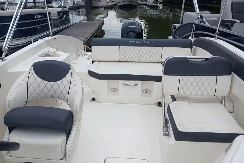 Slide: The Image of 2023 Bayliner DX 2200 boat interior with cushioned seating at a marina. - 7
