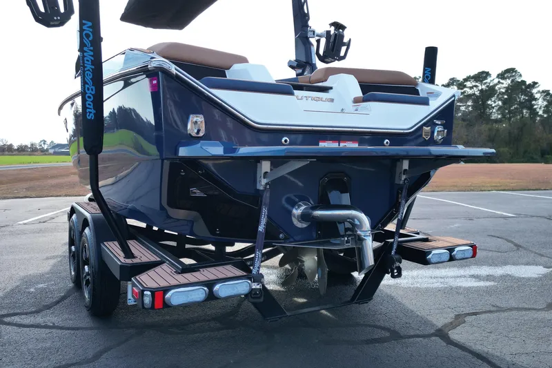 Slide: The Image of 2024 Nautique Super Air Nautique S21 boat on trailer, rear view, showcasing propeller and design. - 18