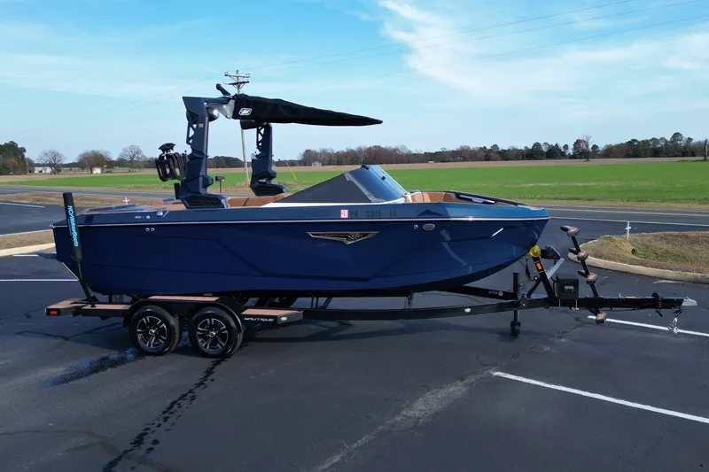 Slide: The Image of 2024 Nautique Super Air Nautique S21 boat on trailer, parked in a lot. - 2