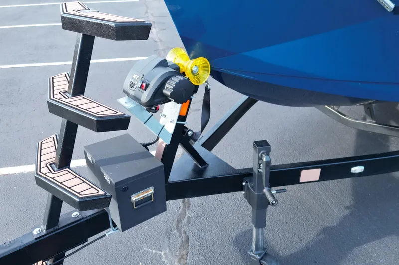 Slide: The Image of 2024 Nautique Super Air Nautique S21 trailer with steps and winch, parked on asphalt. - 21