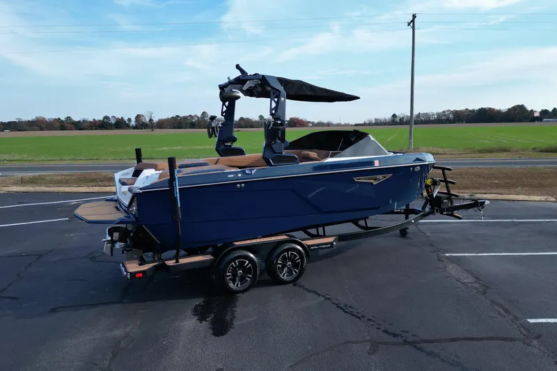 Slide: The Image of 2024 Nautique Super Air Nautique S21 boat on trailer, parked on asphalt near green field. - 4