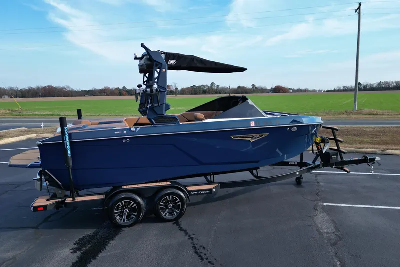 Slide: The Image of 2024 Nautique Super Air Nautique S21 boat on trailer, parked on asphalt near green field. - 8