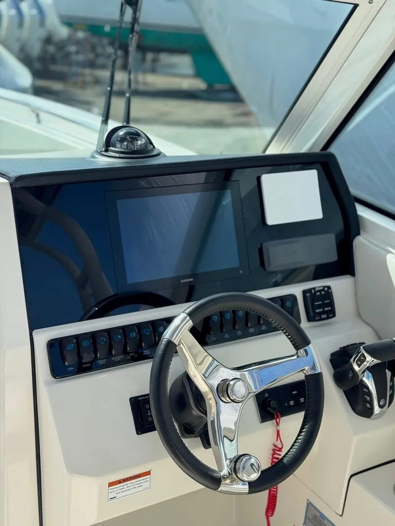 Slide: The Image of 2023 Sailfish 276DC boat dashboard with steering wheel and control panel. - 11