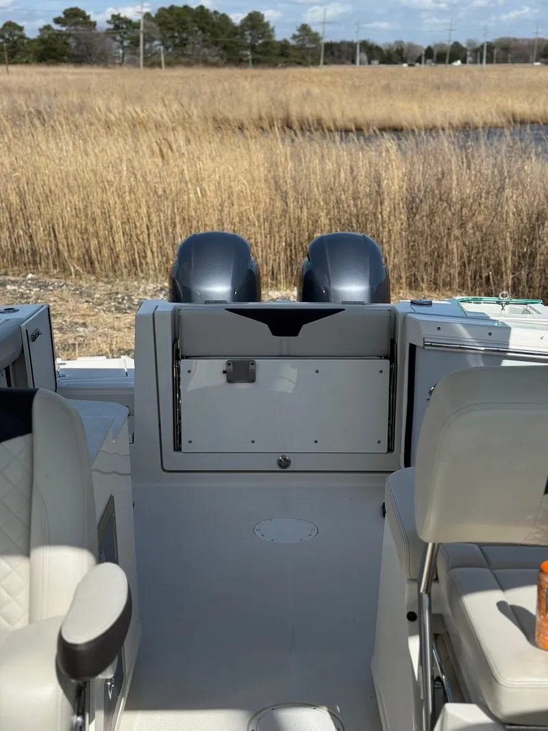 Slide: The Image of 2023 Sailfish 276DC boat interior with dual engines, beige seating, and marshland background. - 12