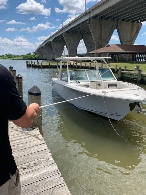Slide: The Image of 2023 Sailfish 276DC boat docked near a bridge on a sunny day. - 2