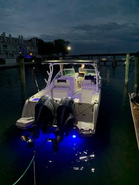 Slide: The Image of 2023 Sailfish 276DC boat docked at night with blue underwater lights. - 3