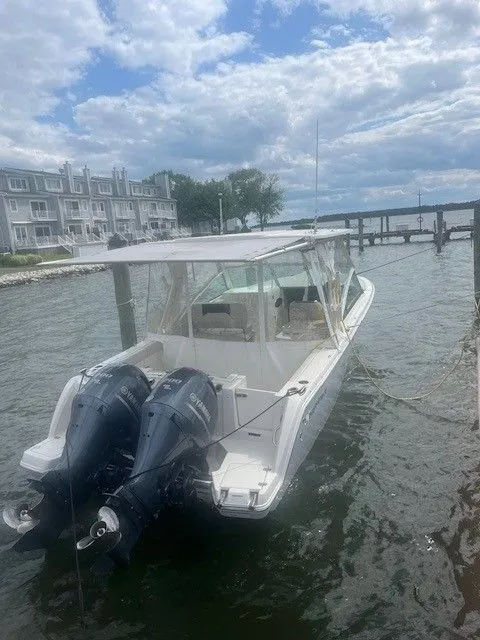 Slide: The Image of 2023 Sailfish 276DC boat docked with dual outboard motors, waterfront view. - 5