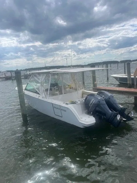 Slide: The Image of 2023 Sailfish 276DC boat docked with dual outboard motors under cloudy sky. - 6