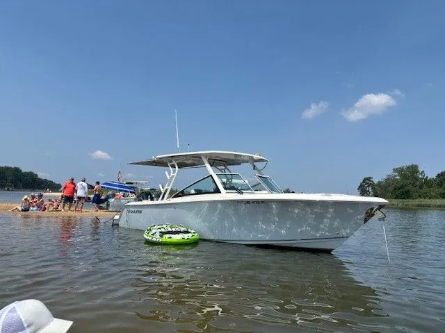 Slide: The Image of 2023 Sailfish 276DC boat anchored near a group of people on a sunny day. - 7
