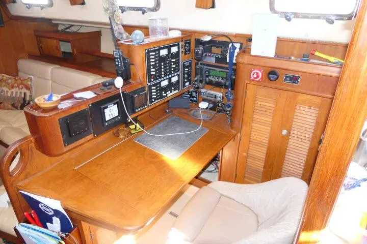 Slide: The Image of Navigation station inside a 1999 Island Packet 45 sailboat, featuring control panels and seating. - 18