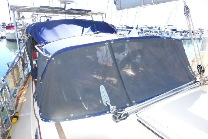 Slide: The Image of 1999 Island Packet 45 sailboat with blue canopy docked at marina. - 33