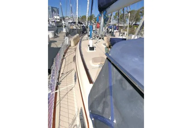 Slide: The Image of 1999 Island Packet 45 sailboat docked at marina, featuring deck and blue canopy. - 36