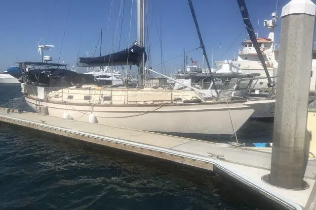 Slide: The Image of 1999 Island Packet 45 sailboat docked at marina under clear blue sky. - 54