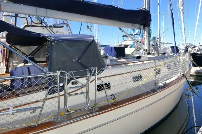 Slide: The Image of 1999 Island Packet 45 sailboat docked in marina, featuring sleek design and netted safety rail. - 57