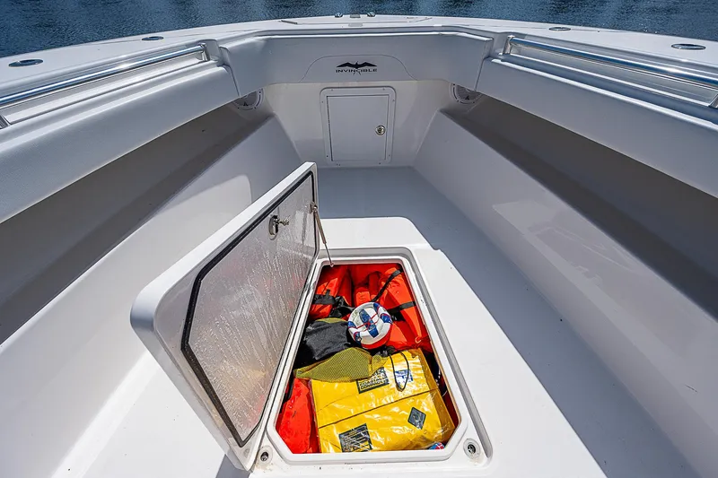 Slide: The Image of Open storage compartment on 2018 Invincible 42 boat, containing life jackets and safety gear. - 15