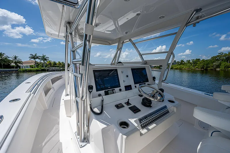 Slide: The Image of 2018 Invincible 42 boat cockpit with modern navigation equipment, steering wheel, and scenic water view. - 5