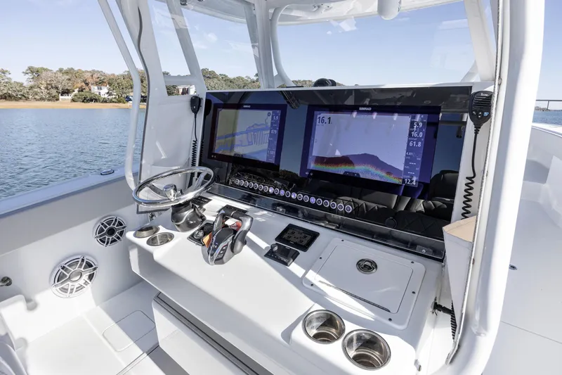Slide: The Image of 2024 Freeman 38 boat dashboard with dual Simrad displays and steering wheel on water. - 17