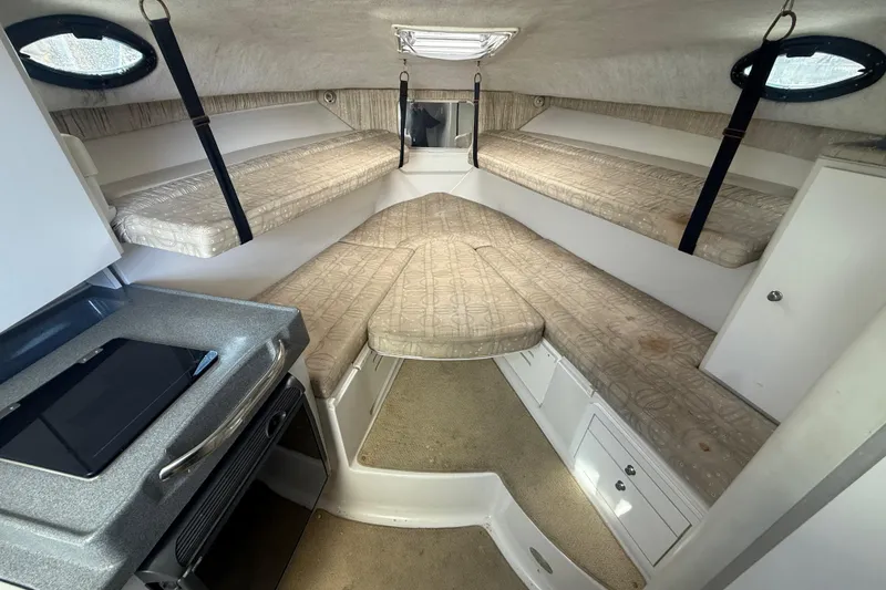 Slide: The Image of 2002 Wellcraft 290 Coastal cabin interior with cushioned berths and compact kitchenette. - 23