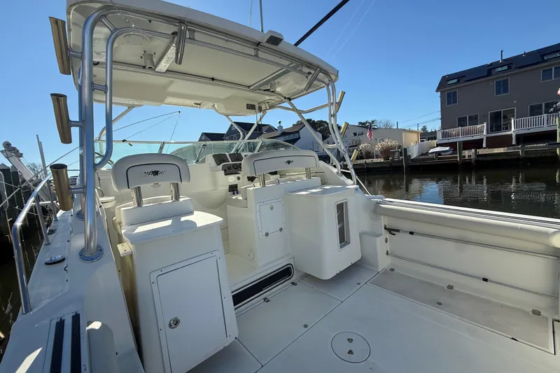Slide: The Image of 2002 Wellcraft 290 Coastal boat interior, featuring helm and seating, docked by waterfront homes. - 8