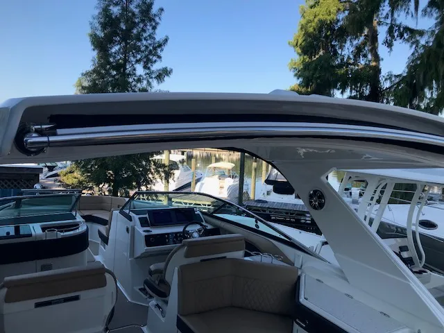 Slide: The Image of 2019 Sea Ray 310 SLX boat interior with modern dashboard and seating, docked by a serene lake. - 26