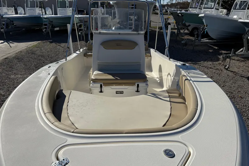 Slide: The Image of 2016 Pioneer 180 Islander boat with beige seating and console, displayed outdoors. - 11