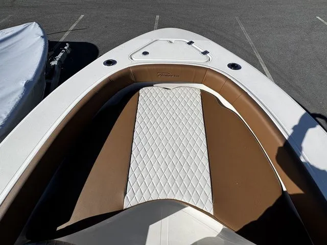 Slide: The Image of 2025 Pioneer Islander 180 boat interior with brown and white seating, parked on asphalt. - 7
