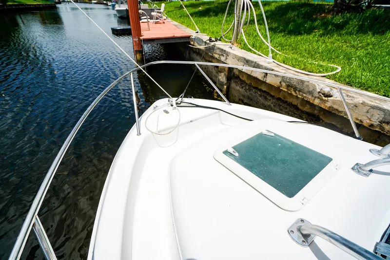 Slide: The Image of 1999 Pro-Line 201 Walkaround boat docked by a canal with green grass and ropes. - 15