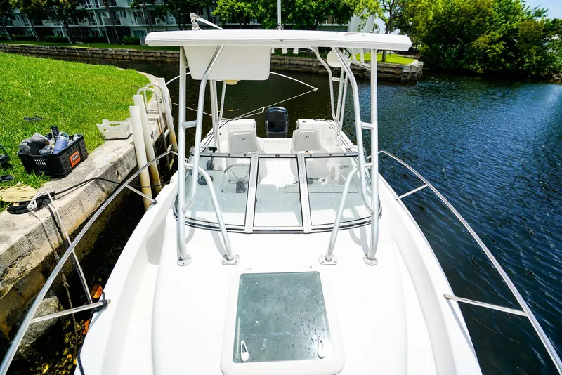 Slide: The Image of 1999 Pro-Line 201 Walkaround boat docked by a canal, featuring a sleek white design. - 16