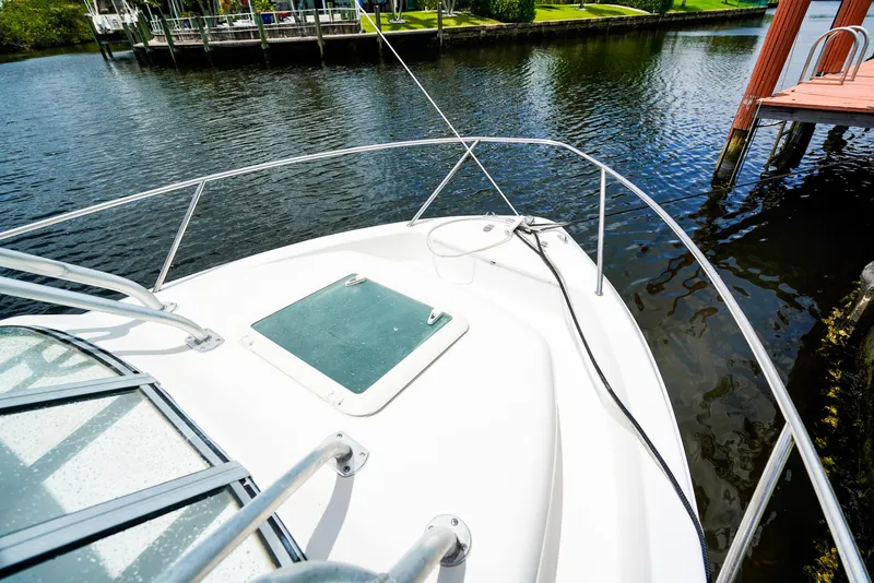 Slide: The Image of 1999 Pro-Line 201 Walkaround boat docked on calm water, featuring a sleek white deck. - 17