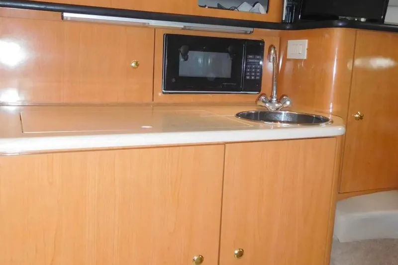 Slide: The Image of 2001 Regal Commodore 2960 yacht kitchen with microwave, sink, and wooden cabinetry. - 16
