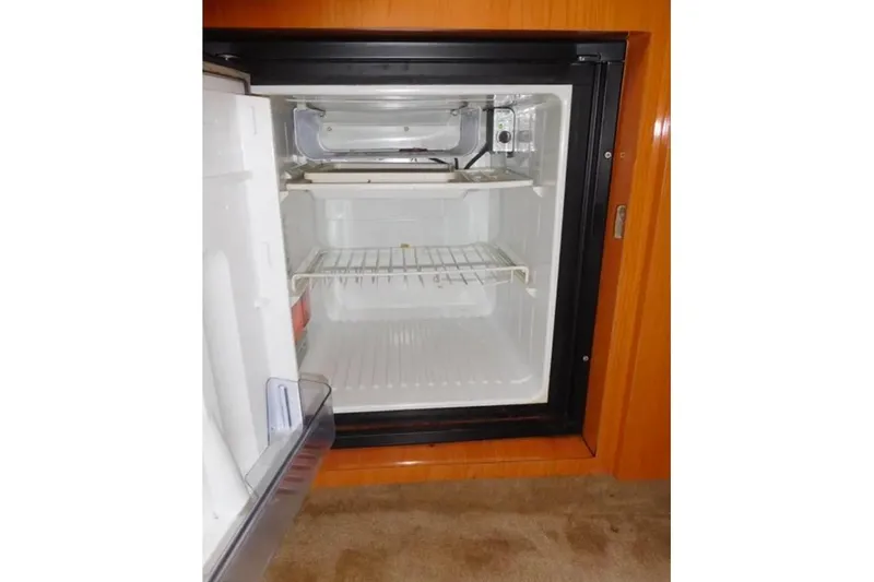 Slide: The Image of Open mini fridge inside 2001 Regal Commodore 2960 boat, showing empty shelves. - 18