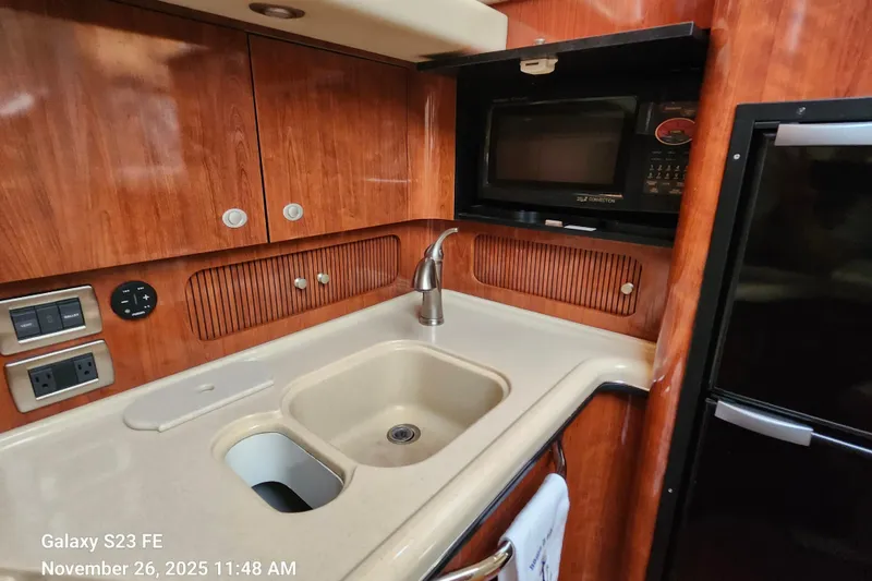 Slide: The Image of 2004 Sea Ray 390 Motor Yacht kitchen with sink, microwave, and wooden cabinetry. - 39