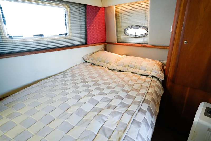 Slide: The Image of Cozy bedroom interior of 2002 Silverton 352 Motor Yacht with checkered bedding and porthole window. - 28