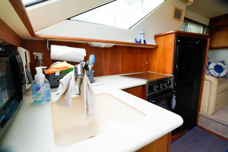 Slide: The Image of 2002 Silverton 352 Motor Yacht kitchen with sink, stove, and wooden cabinetry. - 36