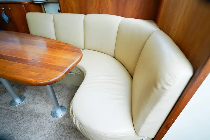 Slide: The Image of 2002 Silverton 352 Motor Yacht interior with curved beige seating and wooden table. - 38