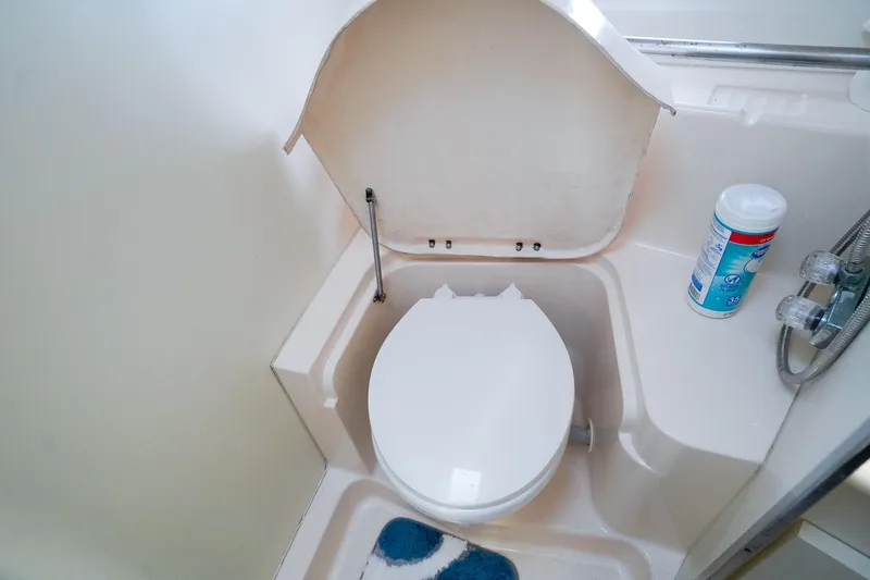 Slide: The Image of 2002 Silverton 352 Motor Yacht bathroom with toilet and cleaning supplies. - 42