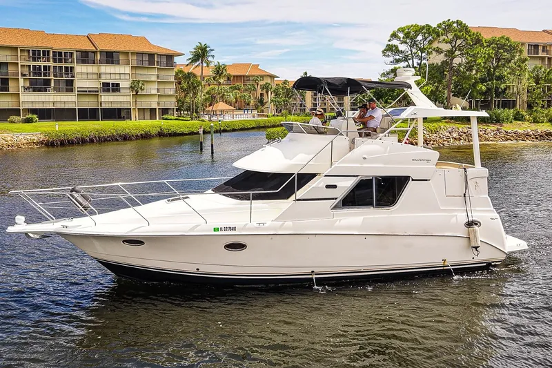 Slide: The Image of 2002 Silverton 352 Motor Yacht cruising on a scenic waterway near residential buildings. - 50