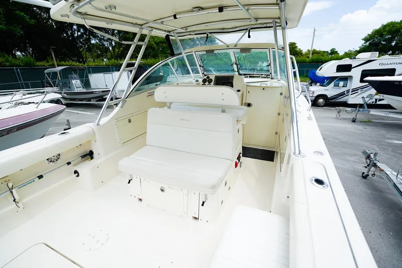 Slide: The Image of 2005 Pursuit 2670 Denali LS boat interior with seating and helm, parked in a marina. - 11