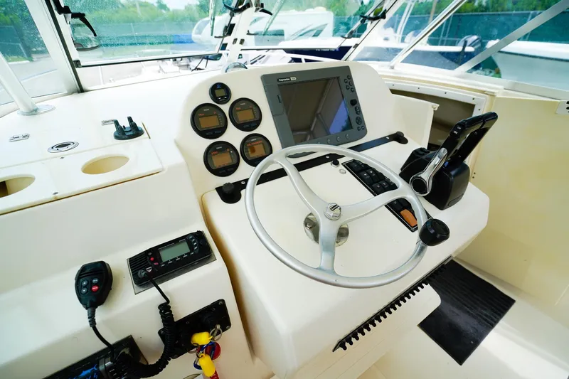 Slide: The Image of 2005 Pursuit 2670 Denali LS boat dashboard with steering wheel and navigation controls. - 15