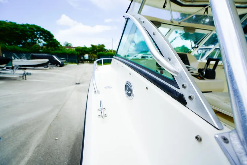 Slide: The Image of 2005 Pursuit 2670 Denali LS boat, close-up of side and interior, parked outdoors. - 22