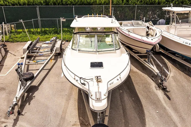 Slide: The Image of 2005 Pursuit 2670 Denali LS boat parked with trailers in a lot. - 29