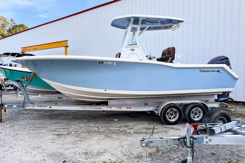 Slide: The Image of 2017 Tidewater 230 CC Adventure boat on trailer, light blue hull, parked outdoors. - 1