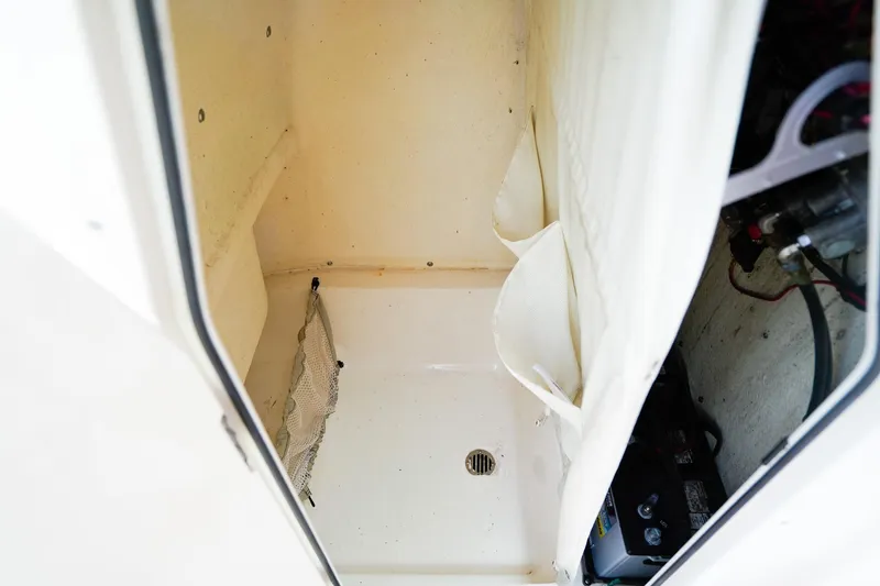 Slide: The Image of 2022 Key West 219 FS boat storage compartment with netting and battery. - 22