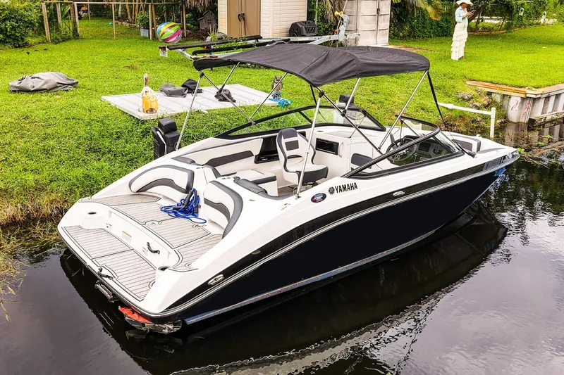 Slide: The Image of 2023 Yamaha Boats SX195 in a serene canal setting with lush greenery. - 2