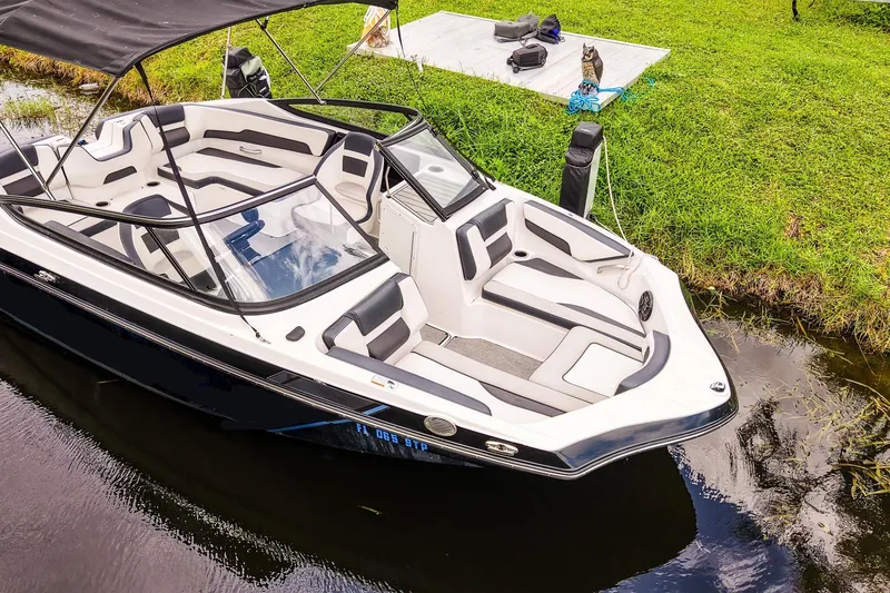 Slide: The Image of 2023 Yamaha Boats SX195 docked on a calm waterway, featuring sleek design and spacious seating. - 21