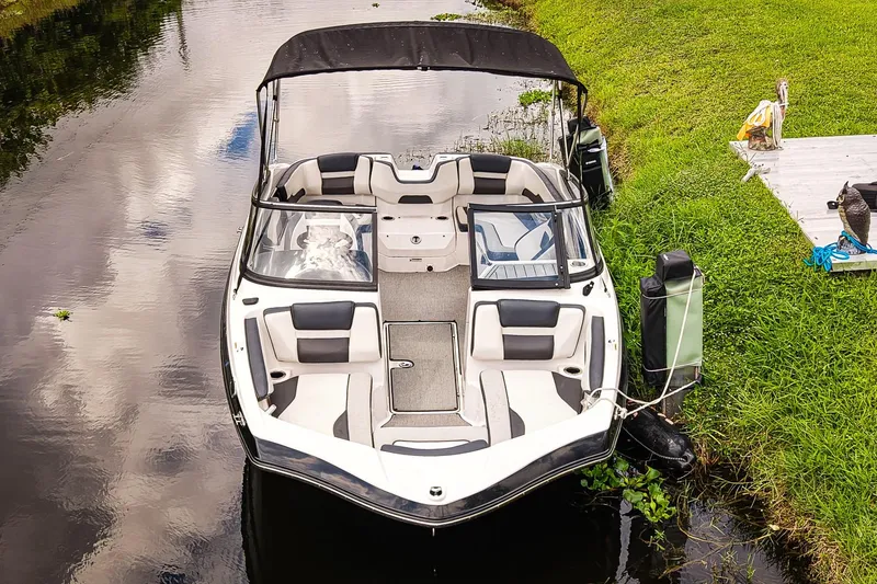 Slide: The Image of 2023 Yamaha Boats SX195 docked on a calm river, surrounded by lush greenery. - 22