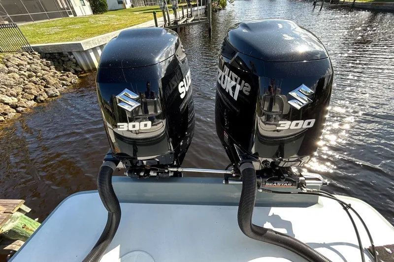 Slide: The Image of Twin Suzuki 300 outboard engines on a 2006 Whitewater 28 boat, docked by a rocky shoreline. - 25