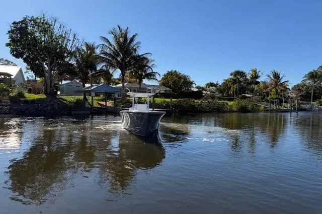 Slide: The Image of 1989 Whitewater 28 boat cruising on a calm river with palm trees in the background. - 28