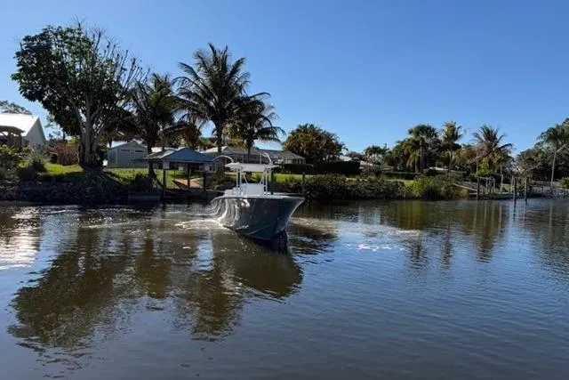 Slide: The Image of 1989 Whitewater 28 boat cruising on a calm river with palm trees in the background. - 29